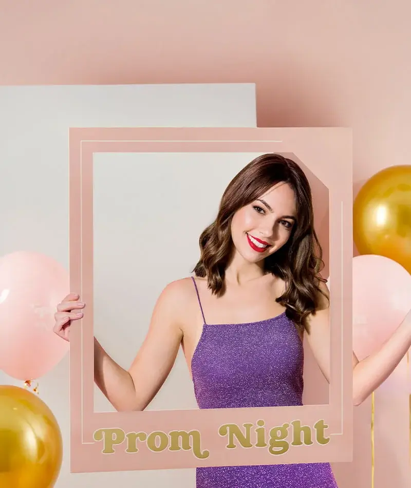 Prom-themed photo frame prop with a person in a purple dress surrounded by gold and pink balloons on a soft peach background Prom-themed photo frame prop with a person in a purple dress surrounded by gold and pink balloons on a soft peach background